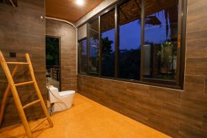 a bathroom with a toilet in a room with windows at Ubud Paras Villa in Ubud