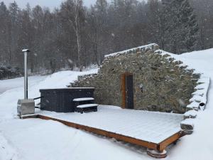 una baita di tronchi nella neve con un mucchio di neve di Domek Wilk w Górach Sowich a Jugów