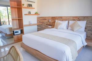 Un dormitorio con una cama blanca y una pared de ladrillo. en Cansa Seminyak, en Seminyak