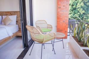 two chairs and a table on a balcony with a bed at Cansa Seminyak in Seminyak