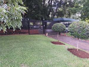 a black fence with two trees in a yard at The Crooked Forest in Pretoria