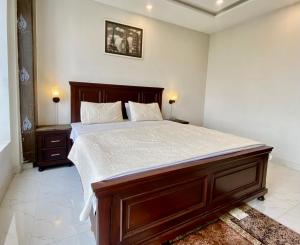 a bedroom with a large wooden bed with white sheets at 1-Bed Elegant Condo at Eiffel TW in Rāmkot