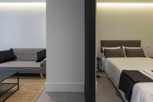 a bedroom with a bed and a couch and a mirror at AT Presidente Nº4 apartamento privado completo in Seville