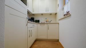 a small kitchen with white cabinets and a wooden floor at Chalet Wohnung Wilder Kaiser in Kitzbühel