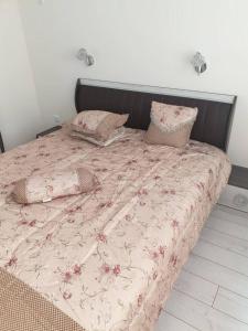 a bed with a pink floral comforter and pillows at Cosy Charming 2-Bed Apartment in Blagoevgrad in Blagoevgrad