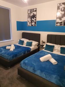 two beds in a room with blue and white at Tudors eSuites Three Bedroom House with Private Garden in Dudley