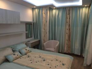 a bedroom with a bed and a chair and curtains at Luxury Two Bedroom Flat in Blagoevgrad