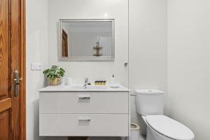 a white bathroom with a toilet and a sink at Casa Estay in Playa Honda