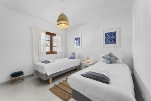 a white bedroom with two beds and a window at Casa Estay in Playa Honda