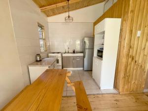 eine Küche mit einem weißen Kühlschrank und einem Holztisch in der Unterkunft Cabañas del Maipo in San José de Maipo