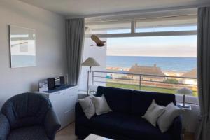 a living room with a couch and a view of the ocean at Strandhotel Wohnung 28 in Dahme