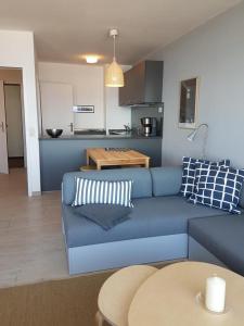 a living room with a blue couch and a kitchen at Strandhotel Wohnung 62 in Dahme