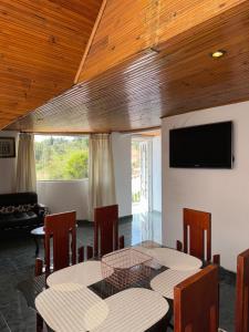 a dining room with a table and chairs and a flat screen tv at Cabaña El Recuerdo, Paipa in Paipa