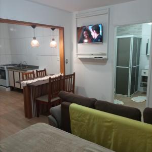 een woonkamer met een bank en een tv aan de muur bij Residencial Dona Preta in Florianópolis