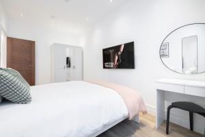 a white bedroom with a bed and a mirror at Luxury 2 Bedroom Apartment in Central London in London