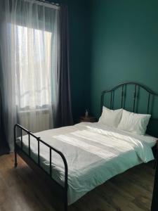 a bed in a blue bedroom with a window at Căsuța de piatră in Buşteni