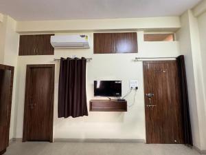 Habitación con 2 puertas y TV en la pared. en Sukoon The Legacy, en Ujjain