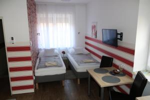 a room with two beds and a table and a tv at Hortobágyi Kemencés Vendégház in Hortobágy
