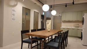 a kitchen with a wooden table and black chairs at SSH Icon Hostel in Seoul
