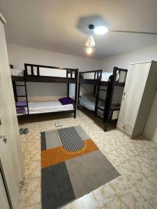 a room with three bunk beds and a rug at Roxy Hostel in Abu Dhabi