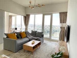 a living room with a couch and large windows at Cozy apartment with Pool - 10 mins from Dubai Marina in Dubai