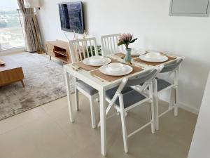 a white dining room table and chairs with plates and flowers at Cozy apartment with Pool - 10 mins from Dubai Marina in Dubai