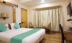 a hotel room with a large bed and a desk at FabHotel Prime Deccan 8 in Pune