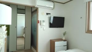 sypialnia z telewizorem na ścianie i łóżkiem w obiekcie SSH Icon Hostel w Seulu