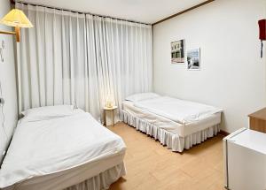 2 łóżka w pokoju z białymi ścianami i zasłonami w obiekcie SSH Icon Hostel w Seulu