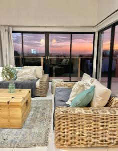 a living room with wicker furniture and a view of the sunset at Alchemy in St Francis Bay