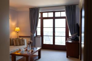una camera d'albergo con divano, tavolo e finestra di Zamek Łeba Resort & Spa a Łeba