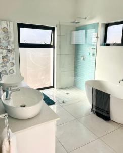Un baño con bañera, lavabo y ducha. en Alchemy, en St Francis Bay