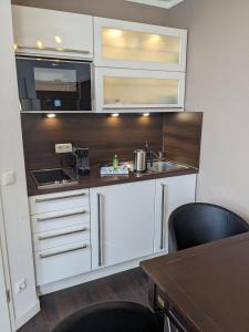 a kitchen with white cabinets and a sink and a table at Yachthafenresidenz-Wohnung-8411-871 in Kühlungsborn
