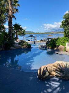 a pool at the beach with a rock in the water at Maranatha Résidence avec plage privée, piscine chauffée in Porto-Vecchio