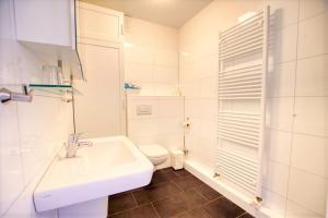 ein weißes Bad mit einem Waschbecken und einem WC in der Unterkunft Strandhotel, App 5SH221 in Heiligenhafen