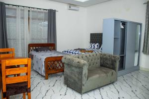a bedroom with a bed and a couch and a chair at Moderní Apartmány Raka in Nungwi