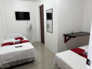 Habitación blanca con 2 camas y TV en RedDoorz near Mariners Legazpi, en Legazpi