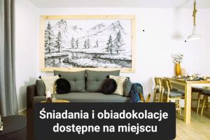 a couch in a living room with a drawing of a mountain at Apartamenty Grapa Resort in Białka Tatrzańska