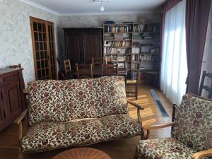 ein Wohnzimmer mit einem Sofa, Stühlen und Bücherregalen in der Unterkunft Chambre 2 dans un appartement in Bourg-en-Bresse