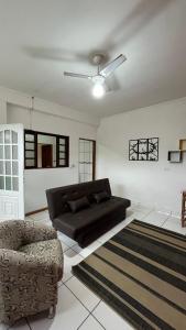 uma sala de estar com um sofá preto e uma cadeira em Suítes em Ubatuba em Ubatuba
