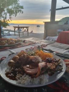 um prato de alimentos com carne e arroz numa mesa em Thumbi View Lodge em Cape Maclear