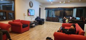 a living room with red couches and a flat screen tv at Haven Lodge Bhurban, 6BR Holiday Home in Hill Station in Bhurban