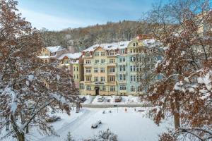 a large yellow building with snow on the ground at Hotel Astoria in Jáchymov