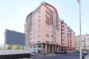 un grand bâtiment rose dans une rue de la ville avec un panneau dans l'établissement Laranjeiras Design by Homing, à Lisbonne