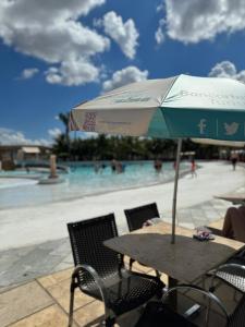 a table with an umbrella in front of a pool at LACQUA Di'Roma, park 24h, cozinha com fogão, 5 pessoas gG in Caldas Novas +1 photo
