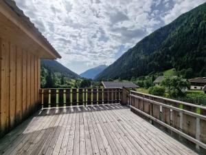 una terraza de madera con vistas a las montañas en Gletscher-Trail Hostel, en Flattach