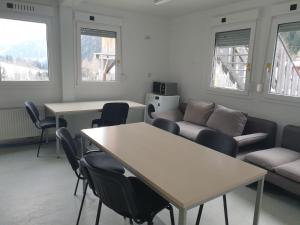 sala de estar con mesas, sillas y sofá en Gletscher-Trail Hostel, en Flattach