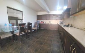 a kitchen with wooden cabinets and a table and chairs at Haven Lodge Bhurban, 6BR Holiday Home in Hill Station in Bhurban