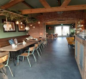 un restaurante con mesas y sillas y una pared de ladrillo en Luxe Tiny House op minicamping in Waarde, en Waarde