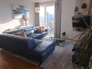 a living room with a blue couch and a large window at Cozy Double Room with Large En Suite Near Canary Wharf London with Amazing Views in a Shared Apartment in London